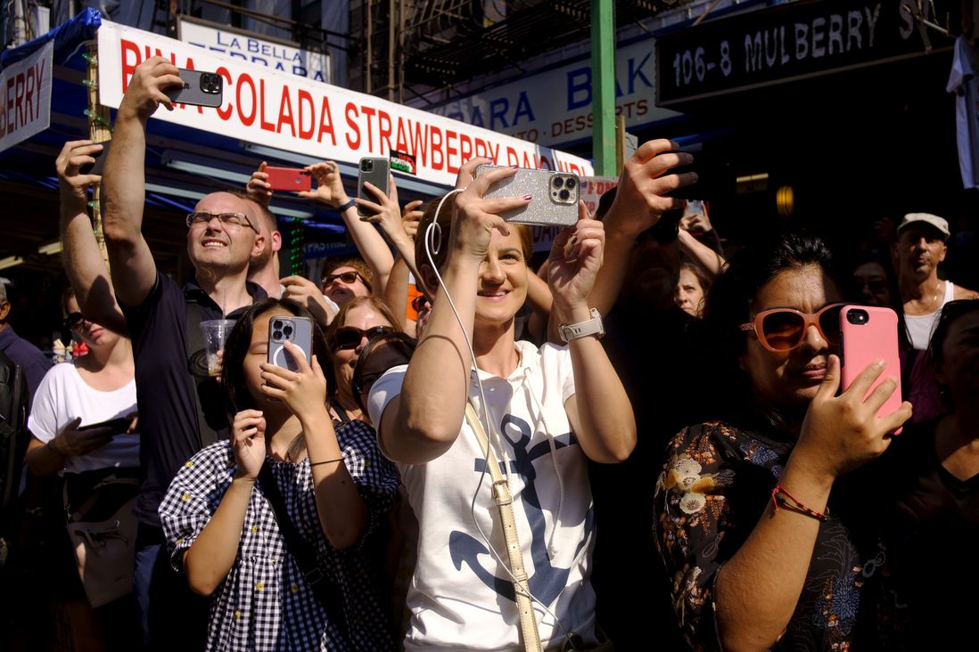 People photograph and record the procession on Mulberry Street.